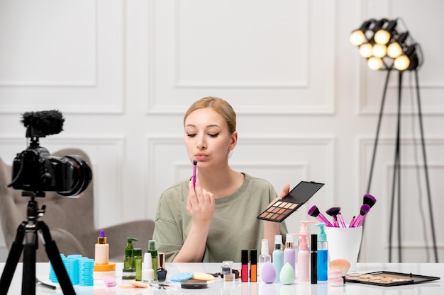 Make-up-Bloggerin, hübsches süßes junges Mädchen, das Make-up-Tutorial vor der Kamera aufnimmt und Lippenstift aufsetzt