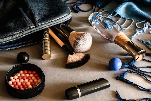 Make-up-Kit Auf dem Tisch sind Rouge-Lippenstift-Eau-de-Parfum-Make-up-Pinsel und eine Tasche für Kosmetika