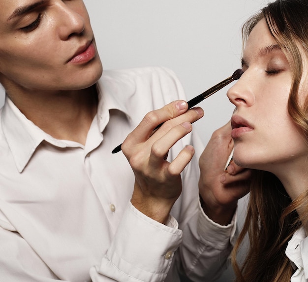 Make-up-Künstler, der Make-up schönes Mädchen-Schönheitskonzept tut und