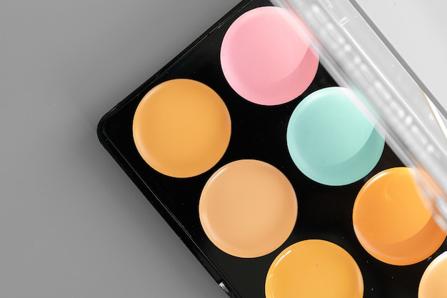 Make-up-Palette mit bunten Concealern auf grauer Oberfläche