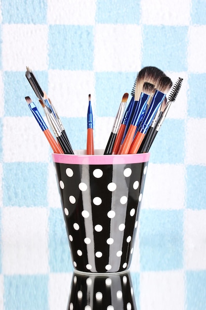 Make-up-Pinsel in einem schwarzen Polkadot-Cup auf buntem Hintergrund