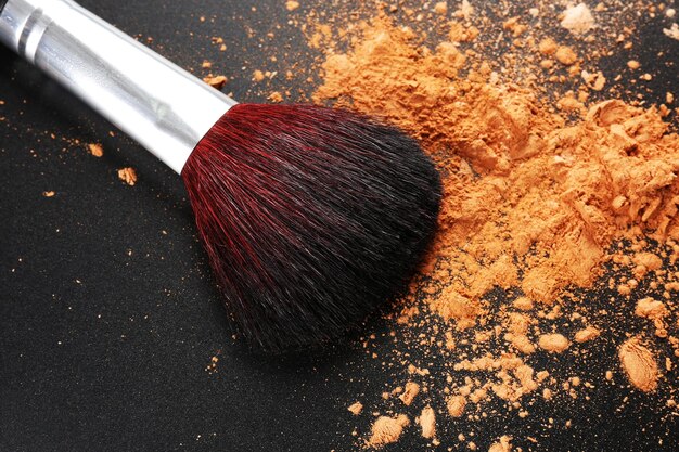 Make-up-Pinsel mit kosmetischem Puder auf dunklem Hintergrund