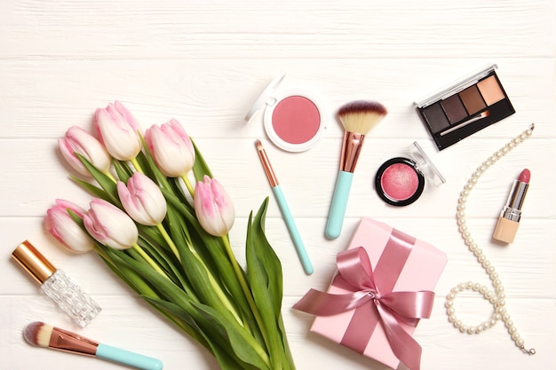 Make-up-Produkte und schöne Frühlingsblumen auf Draufsicht des hölzernen Hintergrundes