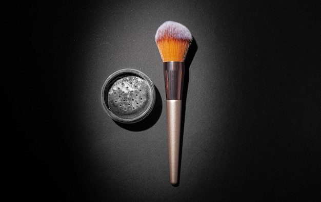 Make-up Puder mit Pinsel auf schwarzem Hintergrund, Nahaufnahme