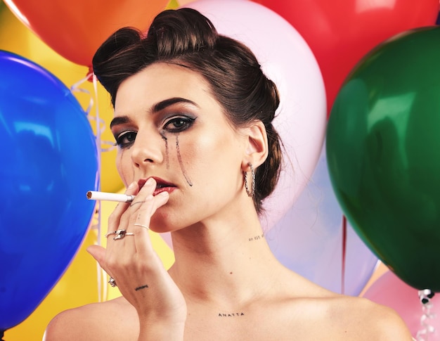 Make-up-Schönheit und Rauchen mit einer Modellfrau im Studio auf einem Ballonhintergrund für Nikotinsucht Porträtkosmetik und Zigarette mit einer Frau, die posiert, um für ein Tabakrauchprodukt zu werben