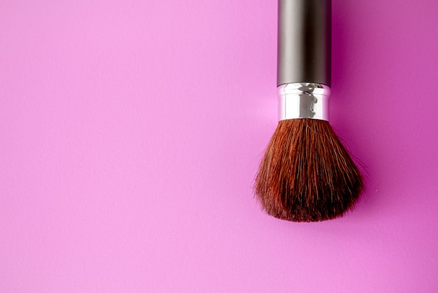 Make-upbürste auf rosa Pastellpapierbeschaffenheitshintergrund