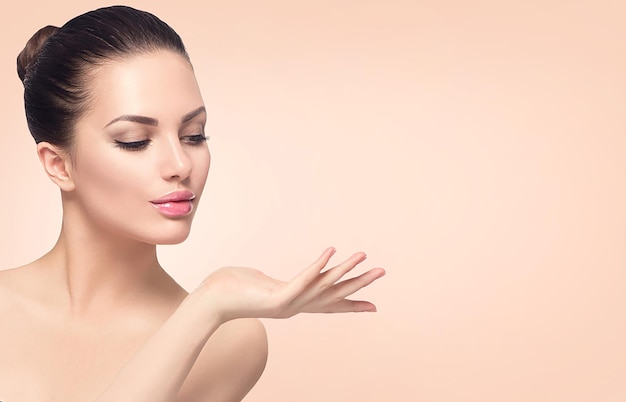 Makellose Spa-Schönheit präsentiert offene Handflächen ideal für Werbung Beige-Hintergrund