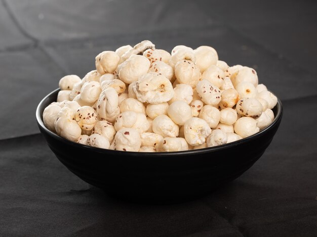 Makhana chiwda ou Foxnuts, mistura de amendoim e chanadal com duas canecas de chá. Makhana ou nozes de raposa são lanches saudáveis com alto valor nutricional são nativas do Sul da Ásia, Punjab, Bihar