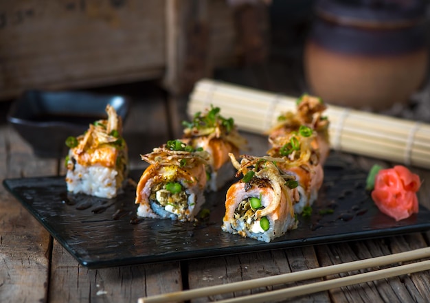 MAKI DE PIEL DE SALMÓN servido en un plato aislado en una vista lateral de fondo de madera