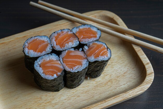 Maki-Röllchen mit Räucherlachs auf einer Holzplatte