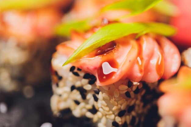 Maki-Sushi-Rollen mit Lachs auf schwarzem Stein auf dunklem Hintergrund Mit Ingwer und Wasabi Sushi-Menü Japanisches Essen Nahaufnahme von köstlichen japanischen Speisen mit Sushi-Rolle Horizontales Foto