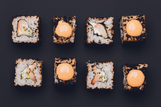 Maki-Sushi-Rollen mit Lachs auf schwarzem Stein auf dunklem Hintergrund Mit Ingwer und Wasabi Sushi-Menü Japanisches Essen Nahaufnahme von köstlichen japanischen Speisen mit Sushi-Rolle Horizontales Foto