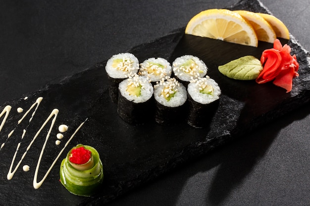 Maki Sushi Rolls mit Gurke oder Avocado auf schwarzem Stein im Dunkeln