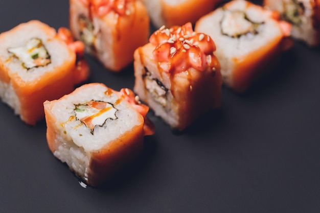 Maki Sushi Rolls con salmón en piedra negra sobre fondo oscuro Con jengibre y wasabi Menú de sushi Comida japonesa Primer plano de deliciosa comida japonesa con rollo de sushi Foto horizontal