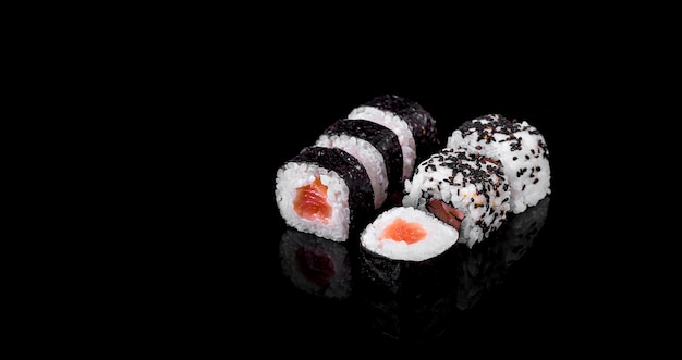 Makis y uramakis auf schwarzem Hintergrund. Japanisches Sushi