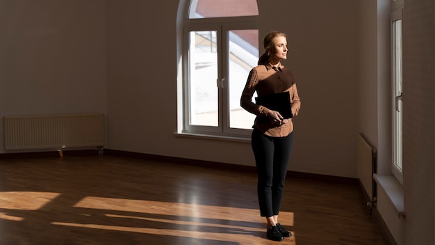 Foto maklerin, die im leeren haus steht und durch das fenster mit kopienraum schaut