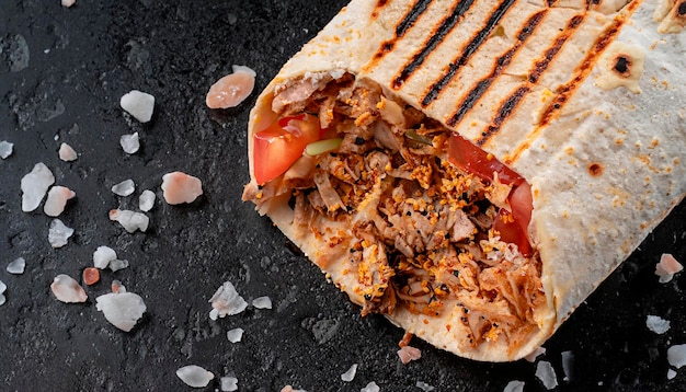 Makro-Aufnahme von Shawarma auf schwarzem Marmor mit Meersalzkrümeln, Zweigen, Top-Viewjpg