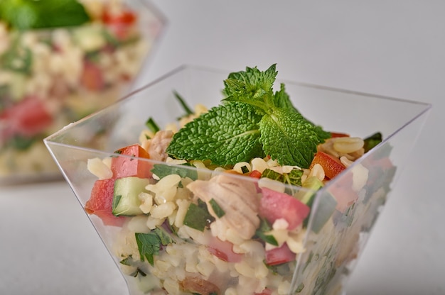 Makro-Tabouleh-Salat mit Petersilien-Minze-Bulgur-Tomaten in transparenter Buffetform auf weiß