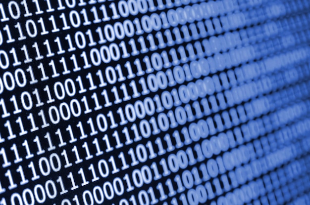 Makroaufnahme des Binärcodes auf dem Monitor eines Bürocomputers Das Konzept der Arbeit des Programmierers Der Fluss digitaler Informationen streicht in klassischer blauer Phantomfarbe