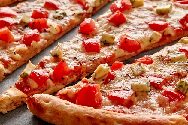 Makroaufnahme einer geschnittenen Pizza mit Mozzarella-Tomaten-Blauschimmelkäse und getrocknetem Basilikum