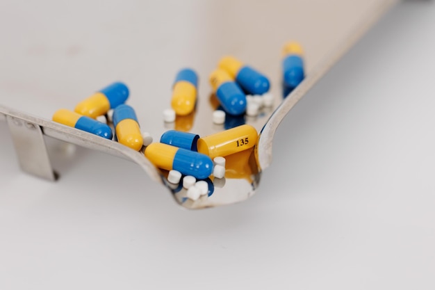 Makroaufnahme von farbigen Pillen und Kapseln während des Produktions- und Verpackungsprozesses in einer modernen pharmazeutischen Fabrik. Herstellungsprozess für Tabletten und Kapseln. Nahaufnahme der Produktionslinie für medizinische Arzneimittel