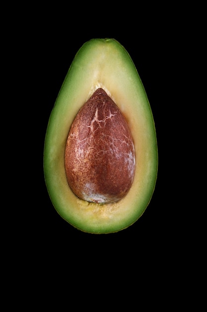 Makroaufnahme von frischen avocados, die auf dem schwarzen hintergrund halbiert werden.