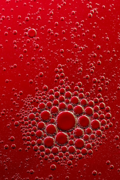 Makrofoto. Ölblasen auf einer Wasseroberfläche. Roter Hintergrund. Rote Farbe in Wasser und Öl.