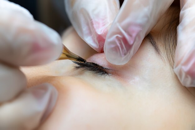 Makrofotografie einer Nadel von einer Tätowiermaschine, die Wimpern-Make-up durchführt
