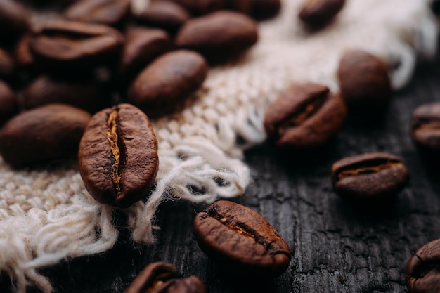 Makrofotografie von Kaffeebohnen liegen auf strukturiertem Holz und Sackleinen Frisch geernteter aromatischer Kaffee Selektive Fokussierung