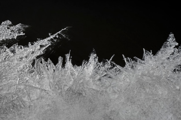 Makroisolierte Textur von feinen Eiskristallen auf Dunkelheit