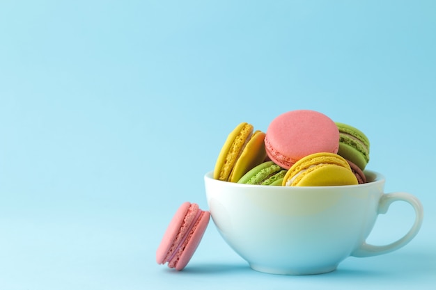 Makronen. Französische bunte Makronenkuchen in einer Tasse. kleiner französischer süßer Kuchen auf hellblauem Hintergrund. Dessert. Süßigkeiten.