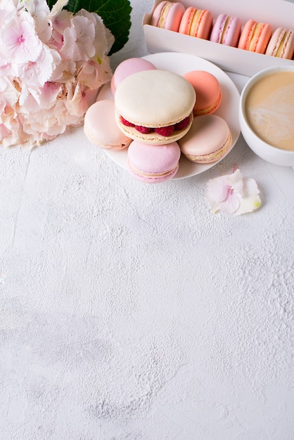 Makronen und Tasse Kaffee mit Blumen über weißer Textur