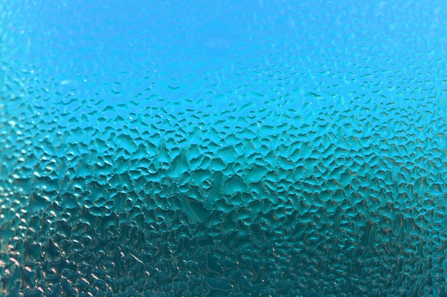 Makroschuß von natürlichen Wassertröpfchen auf Türkis färbte Glas, für abstrakten Hintergrund mit selektivem Fokus
