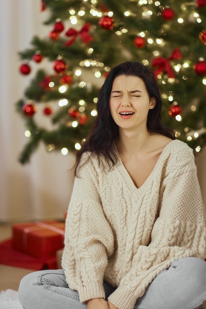 Mal regalo de Navidad mujer decepcionada e infeliz durante las vacaciones de invierno en el interior de casa