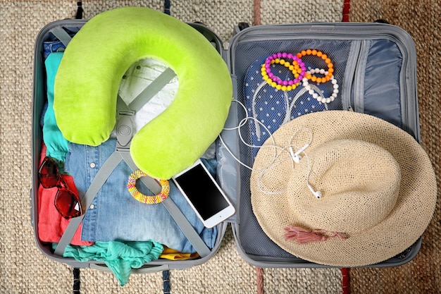 Foto mala com coisas diferentes preparadas para viajar no chão