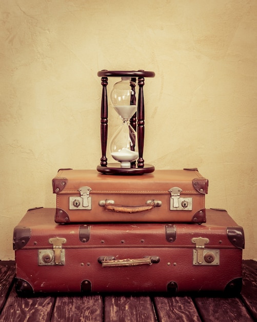 Foto mala de couro marrom clássico vintage e relógio de areia retrô. conceito de negócio de agência de viagens