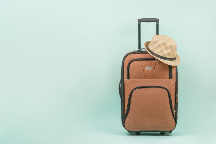 Mala de viagem com chapéu de homem sobre fundo azul. Espaço para o texto.