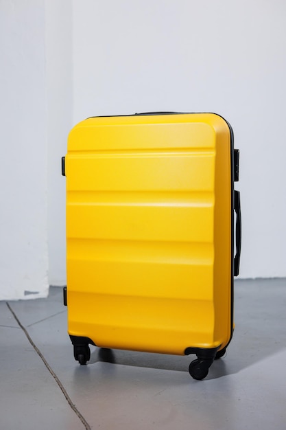 Mala forte de plástico amarelo para transportar bagagem em um fundo branco Uma mala brilhante para viagens