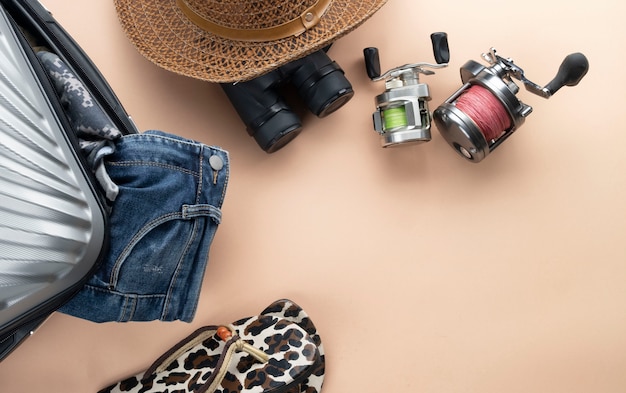 Foto mala plana leigos cinza com binóculos, chapéu, jeans, girando para a pesca e sandálias. conceito de viagens