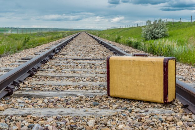 Mala vintage no meio de trilhos de trem nas pradarias