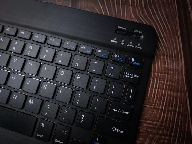 Malasia30 de abril de 2022 Teclado inalámbrico Bluetooth negro sobre fondo de madera