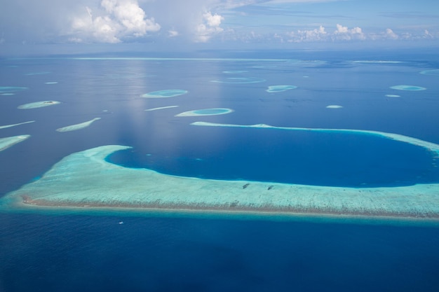 Maldivas desde la vista aérea, arrecifes de coral poco profundos con horizonte marino. Increíble destino escénico