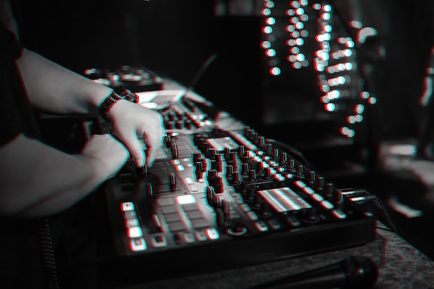 Male DJ mezcla música electrónica en un controlador de música profesional en una discoteca en una fiesta. Foto en blanco y negro con efecto de falla de realidad virtual