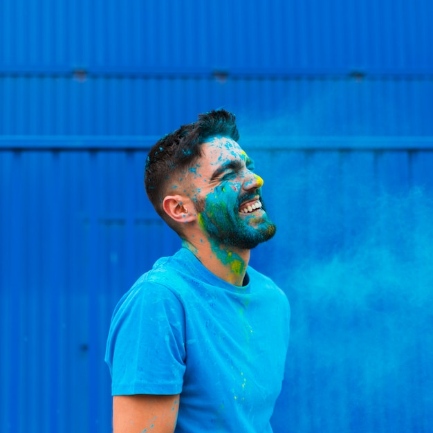 Foto malen sie den befleckten jungen mann, der auf holi-festival lacht