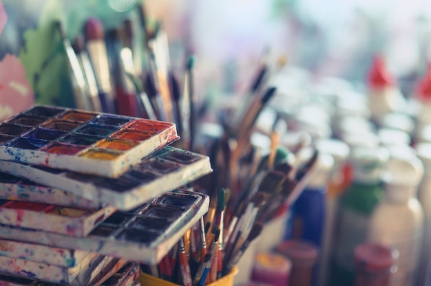 Malen Sie Pinsel und Aquarellfarben in einer Werkstatt auf den Tisch