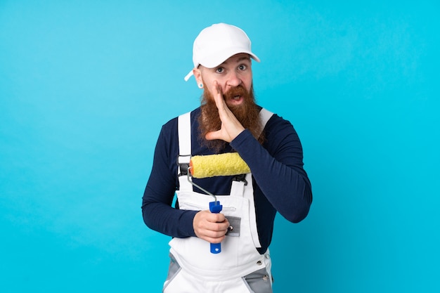 Maler Mann mit langem Bart über isolierter blauer Wand, die etwas flüstert