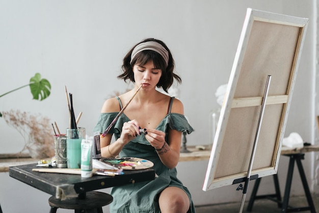 Maler sitzt auf einem Hocker am Staffeln im Kunststudio