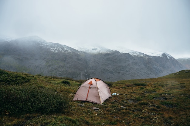 Malerische Alpenlandschaft mit Zelt auf grünem Hügel