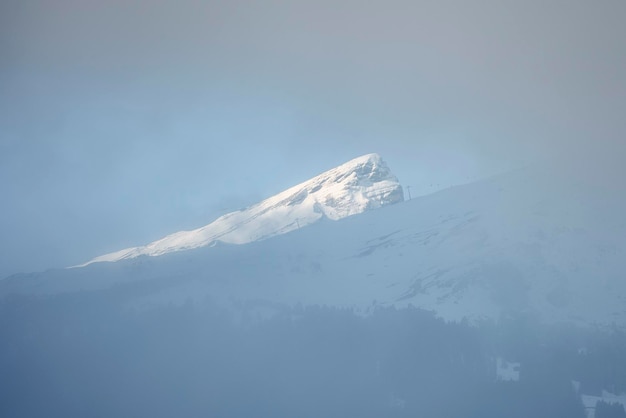 Malerische Aussicht auf den schneebedeckten Berggipfel durch Nebel gesehen