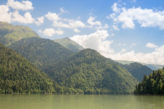 Malerische Aussicht auf eine Bergkette und einen ruhigen See unter bewölktem Himmel an einem sonnigen Urlaubstag